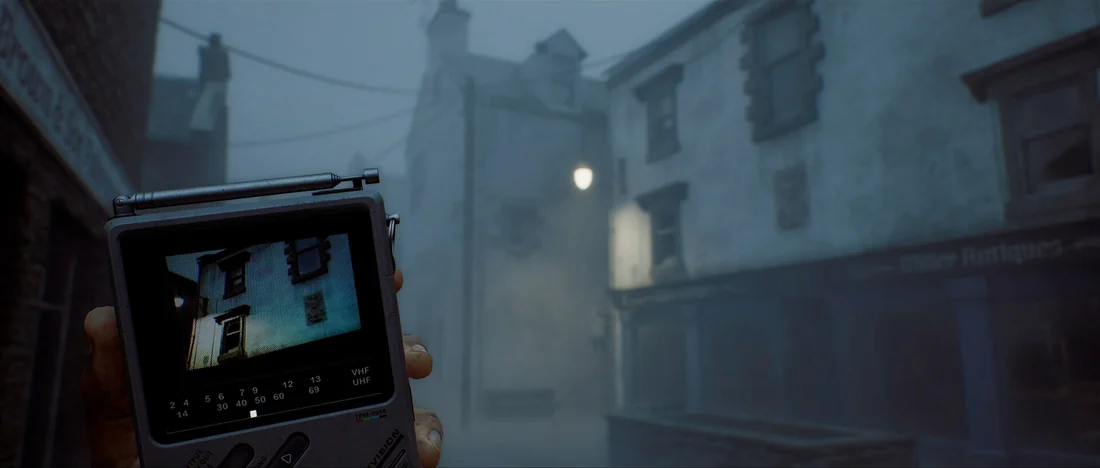A handheld CRTV displays a building while facing a foggy street in an official Silent Hill: Townfall image.